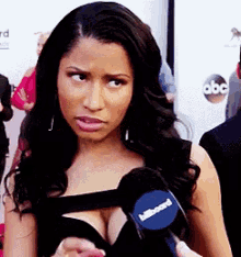 a woman in a black dress is talking into a microphone that says billboard on it