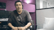 a man wearing a timberland shirt is sitting in a chair in front of a computer .