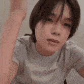a close up of a person wearing a white t-shirt with their hand in the air .