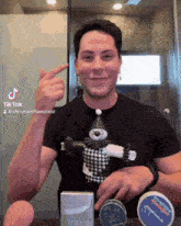 a man in a black shirt is holding a stuffed clown and pointing at his finger
