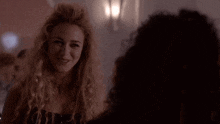 a woman with curly hair and a cross necklace