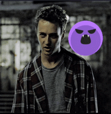 a man in a plaid shirt stands in front of a purple circle with a face on it