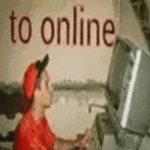 a man is sitting in front of a computer with the words `` to online '' written on the wall .