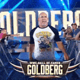 a man in a goldberg shirt stands in front of a sign that says wwe hall of fame goldberg