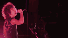 a man singing into a microphone with purple lights in the background