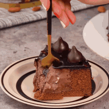 a piece of chocolate cake on a plate with a gold spoon