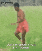 a shirtless man in a red skirt is walking through a field .