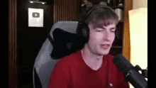 a young man wearing headphones is sitting in front of a microphone in a room .
