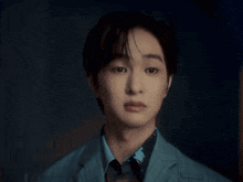 a young man in a suit and tie looks at the camera with a serious look on his face