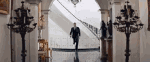 a man in a suit is running down a staircase in a hallway