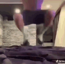 a man is standing on a bed with his legs crossed .
