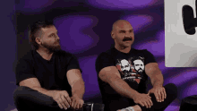 two men are sitting next to each other with one wearing a shirt that says warwood