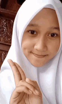 a girl wearing a white hijab and a white shirt is smiling