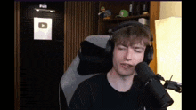 a man wearing headphones is sitting in a chair in front of a microphone in a room .