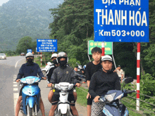a group of people riding motorcycles in front of a blue sign that says km 503 000