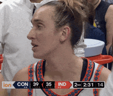 a female basketball player stands in front of a scoreboard that says con 39 35 ind 2nd 2:31 14
