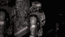 a black and white photo of a soldier in armor holding a gun .