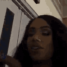 a woman with long hair and a nose ring is standing in front of a door in a dark room .