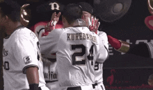 a baseball player with the number 24 on his back is hugging another player