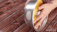 a person is holding a cake pan on a wooden table with the words made in animatica on the bottom