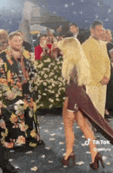 a woman in a high heeled dress is standing on a carpet .