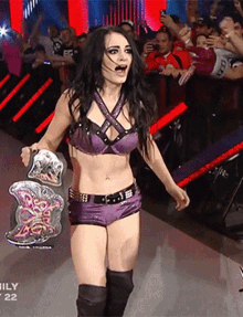a woman in a purple outfit is holding a wrestling championship belt with the number 22 on it