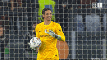 a soccer goalie wearing a betsson jersey holds a soccer ball