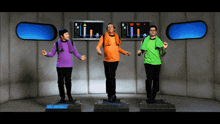 three people are dancing in front of a monitor that says ' ii ' on it