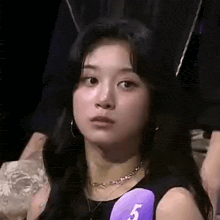 a close up of a woman 's face with a purple sticker on her neck .