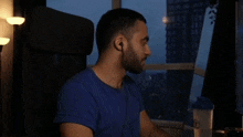 a man in a blue shirt is sitting in a chair