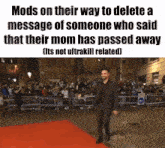 a man in a suit is walking on a red carpet in front of a crowd