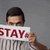 a man is holding a sign that says stay #