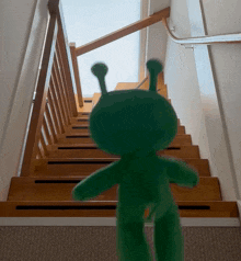 a stuffed green alien is walking up a set of stairs