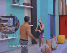 a man without a shirt is standing next to a woman in a living room with a red door that says tierra