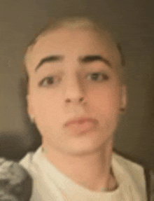 a close up of a young man 's face with a white shirt on .