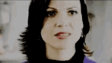 a close up of a woman 's face with a purple sweater and black top .