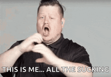 a man is making a heart shape with his hands and the words this is me all the sucking are above him