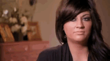 a woman with long hair is making a funny face while sitting in front of a dresser .