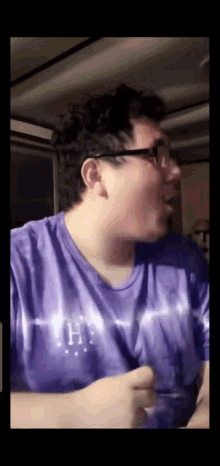 a man wearing a purple shirt with the letter h on the front