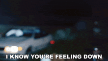 a blurry picture of a car with the words " i know you 're feeling down " below it