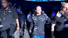 a man wearing a jacket that says ufc walks into a stadium