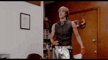 a man in a leather vest and silver pants is standing in front of a door
