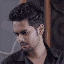 a man with a beard is wearing a black shirt and looking to the side