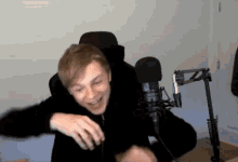 a man is sitting in front of a microphone and smiling