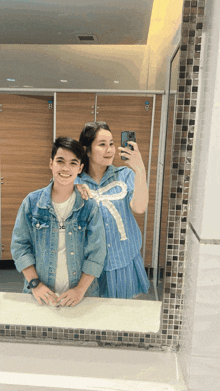 a man and a woman are taking a selfie in front of a mirror