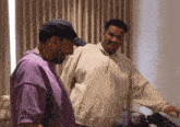 two men are standing next to each other and one has a hat on