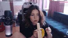 a girl is eating a banana in front of a microphone with the number 36 visible