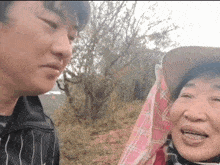 a man and a woman are standing next to each other in a field and smiling .