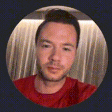 a man in a red shirt is in a circle with a curtain behind him