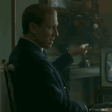 a man in a suit and tie is sitting in a chair smoking a cigar .